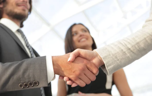 Businesspeople  shaking hands against room with large window loo — Stock Photo, Image