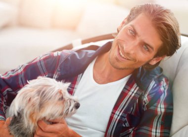 yakışıklı olan büyük bir koltukta otururken köpeğini okşayarak.