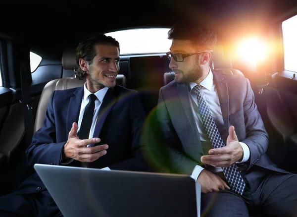 Two businessman talking while sitting in the car — Stock Photo, Image