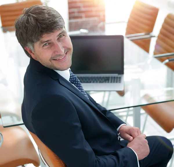 Gerente sorrindo sentado na mesa de trabalho na sala de reuniões . — Fotografia de Stock