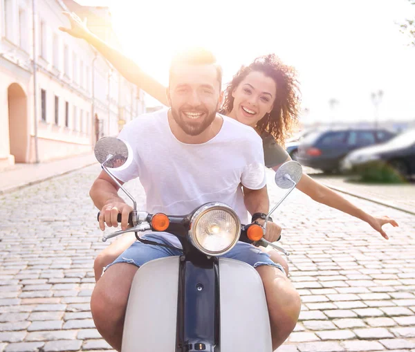 Cheerful young couple riding a scooter and having fun — Stock Photo, Image