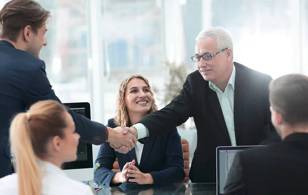 Partner commerciali stringono la mano nella sala conferenze — Foto Stock