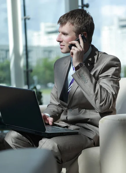 Atrakcyjny facet Europejskiej rozmowy na telefon podczas korzystania z laptopa. — Zdjęcie stockowe