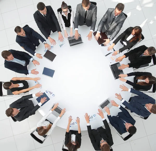Grupo de empresarios sentados en la mesa redonda, y poniendo sus palmas sobre la mesa —  Fotos de Stock