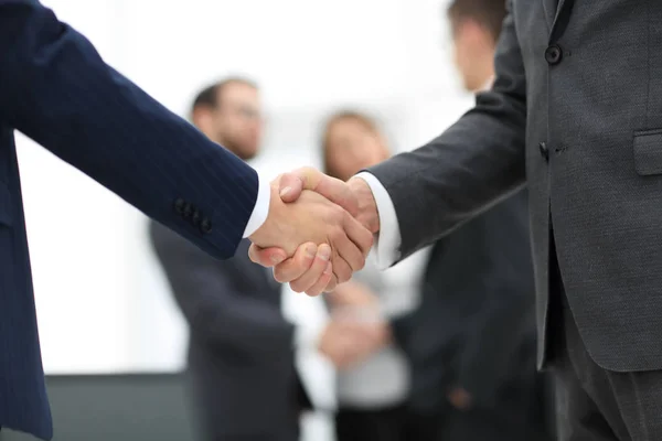 Dos hombres de negocios estrechando la mano con sus colegas de fondo. —  Fotos de Stock