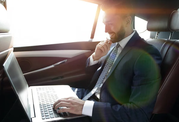 Uomo d'affari digitando testo sul computer portatile mentre seduto in auto — Foto Stock