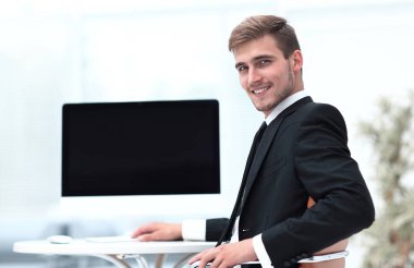 Masada oturan ve kameraya bakarak başarılı iş adamı.
