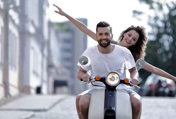 Happy young couple riding a scooter in the city on a sunny day — Stock Photo, Image