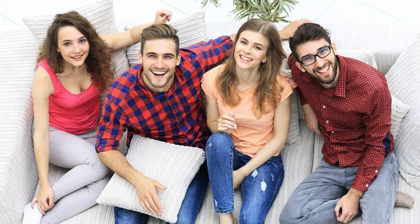 four happy friends laughing while sitting on the couch