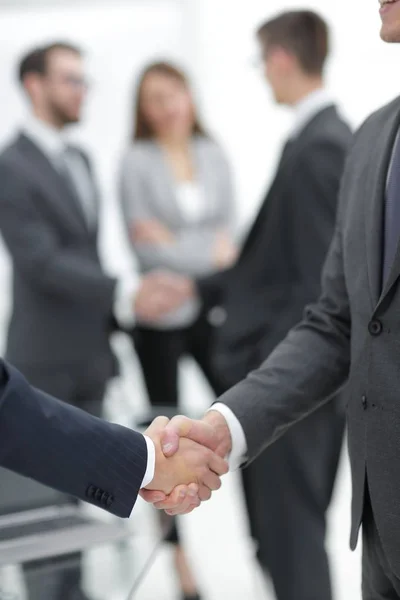 Dos hombres de negocios estrechando la mano con sus colegas de fondo. —  Fotos de Stock