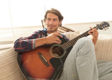oturma odasında kanepede oturup gitar ile Modern adam.