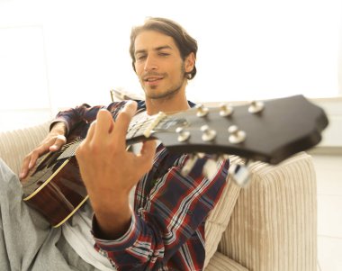 gitar oturma odasında kanepede oturan adam. bir yaşam tarzı kavramı