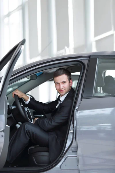 .successful businessman sitting behind the wheel of a new car — Stock Photo, Image