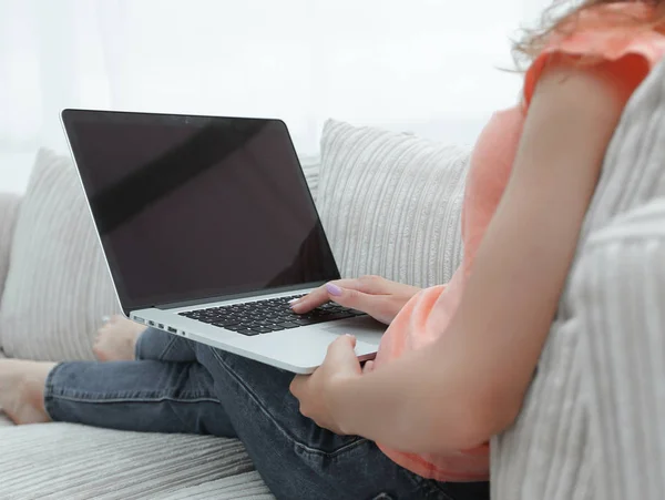 Молодая женщина работает с ноутбуком сидя на диване — стоковое фото