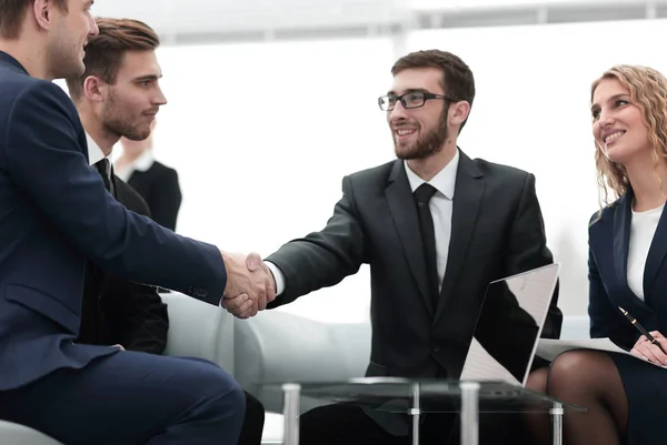 Partner che concludono un accordo e stringono la mano alla presenza dei membri del team — Foto Stock