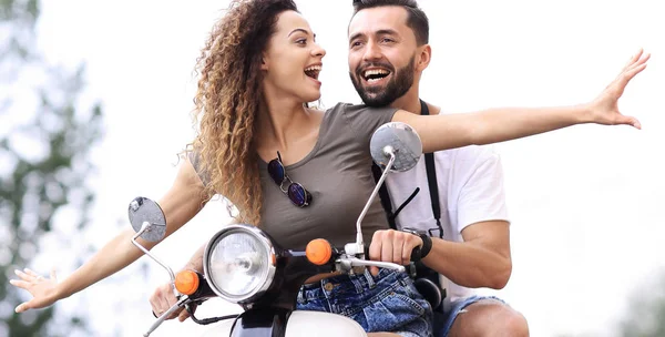 Attractive couple riding a scooter on a sunny day in the city — Stock Photo, Image