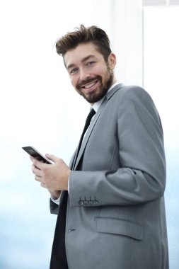 Takım elbiseli şık adam telefonla bilgi okuyor.