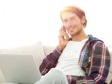 cep telefonu üzerinde konuşurken laptop ile ciddi genç adam