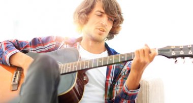 Yakışıklı adam evde kanepede gitar çalmaya