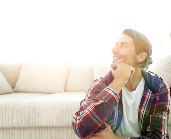 Close-up de um cara feliz sentado no tapete em um novo apartamento — Fotografia de Stock