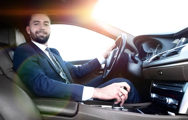 View from the side confident businessman sits at the wheel of a car — Stock Photo, Image