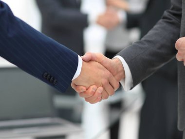 İş ortakları iş yerlerindeki iş eşyalarının üzerinden el sıkışıyor