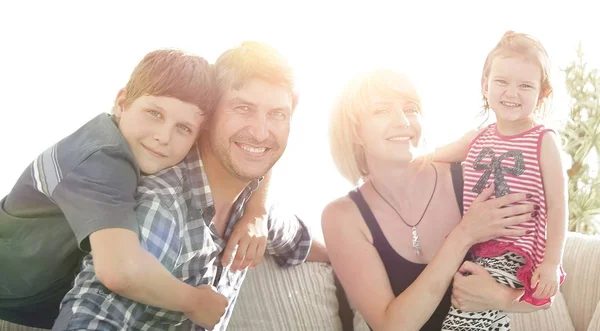 Šťastná rodina čtyř sedí na pohovce — Stock fotografie