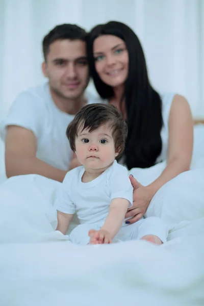 Pasangan bahagia dan anak duduk di tempat tidur — Stok Foto