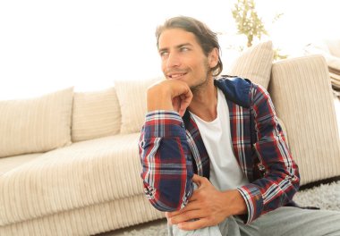 Samimi bir oturma odasındaki halının üzerinde oturan rüya gören bir adamın yakın çekimi.