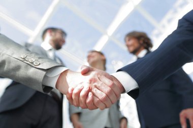 İş ortaklarının el sıkışması ön planda.