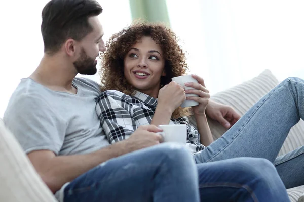 Pareja amorosa sentada en un sofá en la sala de estar — Foto de Stock