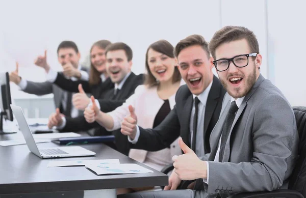 Equipo de negocios con los pulgares hacia arriba mientras está sentado en su escritorio — Foto de Stock