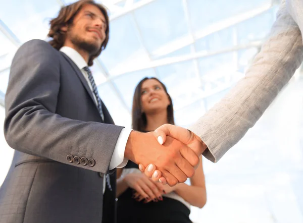 Empresarios estrechando la mano contra la habitación con grandes ventanales — Foto de Stock