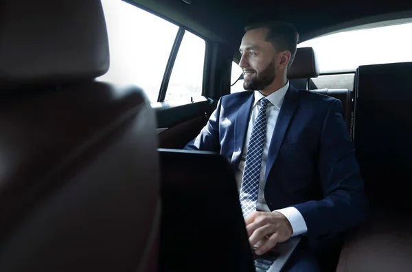 Usmívající se podnikatel s notebookem sedět v autě — Stock fotografie
