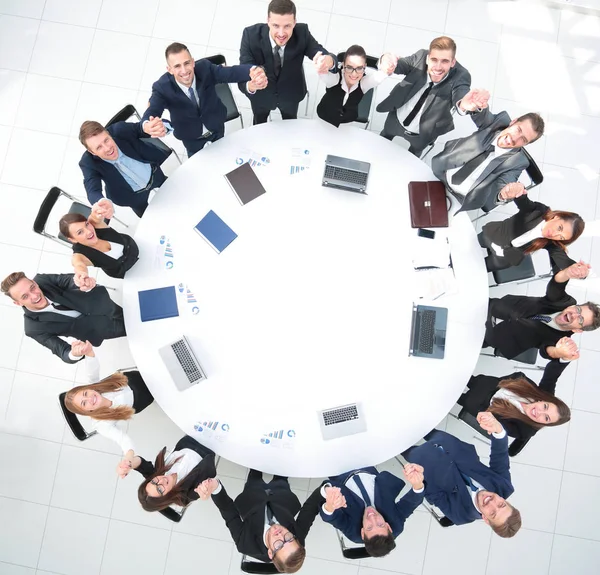 Diretor e equipe de negócios sentados na mesa redonda e segurando as mãos uns dos outros . — Fotografia de Stock