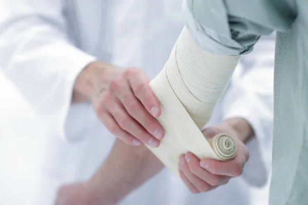 Médico que aplica vendaje elástico en el codo del paciente . — Foto de Stock