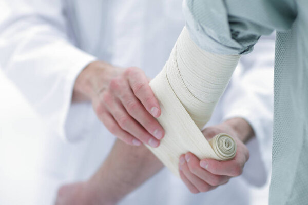 doctor applying elastic bandage on the elbow of the patient.
