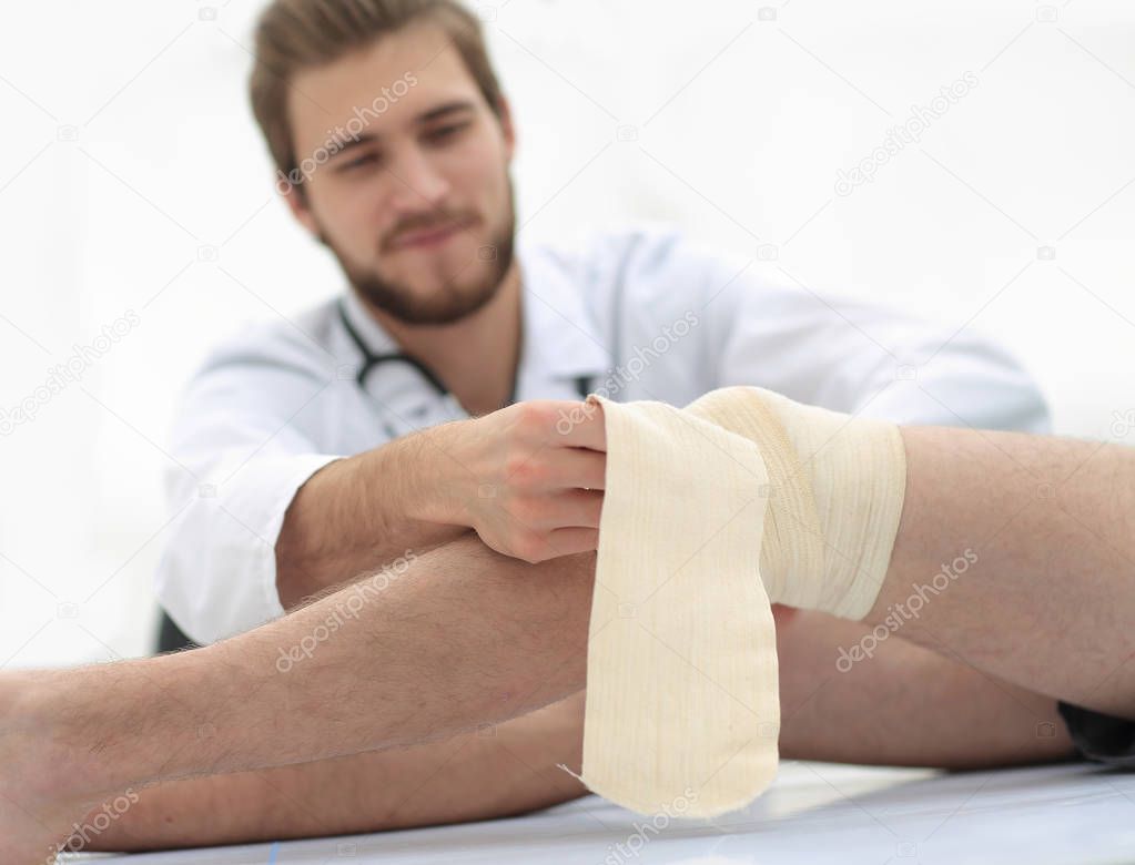 doctor bandaging a wound on the leg of the patient