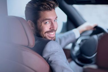 Başarılı bir adam prestijli bir arabanın direksiyonunda oturuyor.