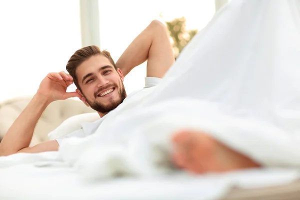 Primo piano.uomo sorridente che riposa in camera da letto — Foto Stock