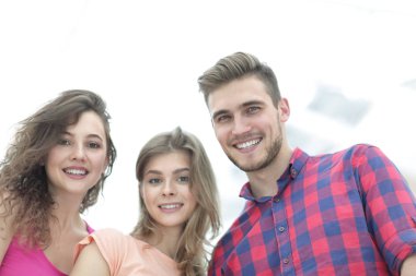 Beyaz arka planda gülümseyen üç genç insana yakın çekim