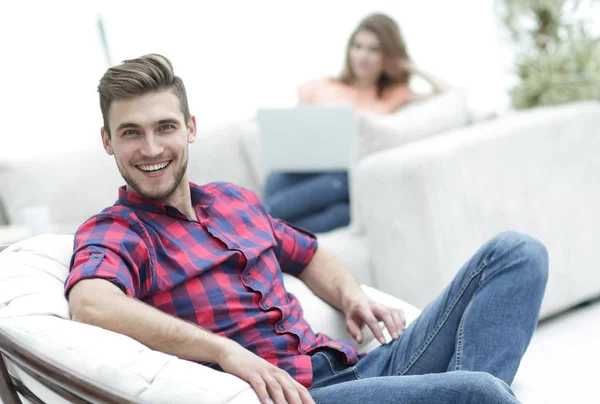 Glücklicher junger Mann sitzt in einem großen Stuhl auf verschwommenem Hintergrund — Stockfoto