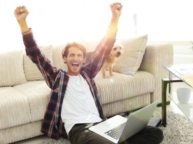 mutlu genç adam köpeğiyle oturma odasında exults