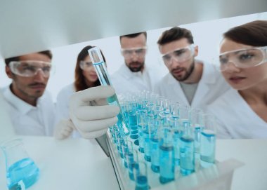 arka plan görüntüsü sıvı cam tüp içinde eğitim microbiologists oluşan bir gruptur.