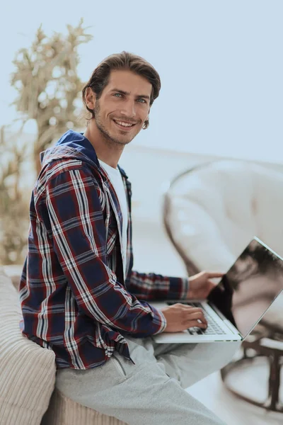 Joven con estilo que trabaja en el ordenador portátil y mirando a la cámara —  Fotos de Stock