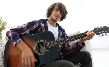 adam bir şarkı söyler ve kanepede oturan gitar çalar.