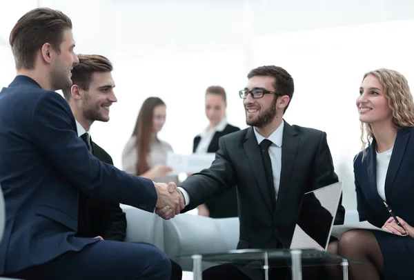 Socios concluyendo trato y estrechando la mano en presencia de los miembros del equipo —  Fotos de Stock