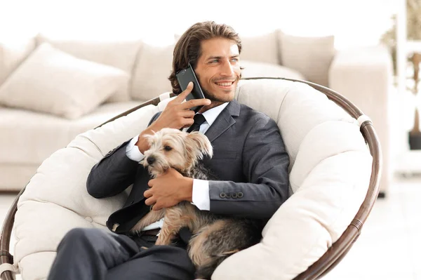 successful businessman holds his dog and pet and talks on the smartphone