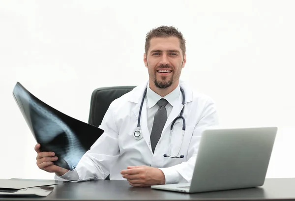 Läkaren undersöker en x-stråle, sitter bakom ett skrivbord — Stockfoto