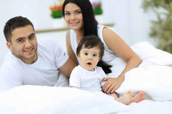 Família alegre se divertindo juntos deitados em uma cama — Fotografia de Stock